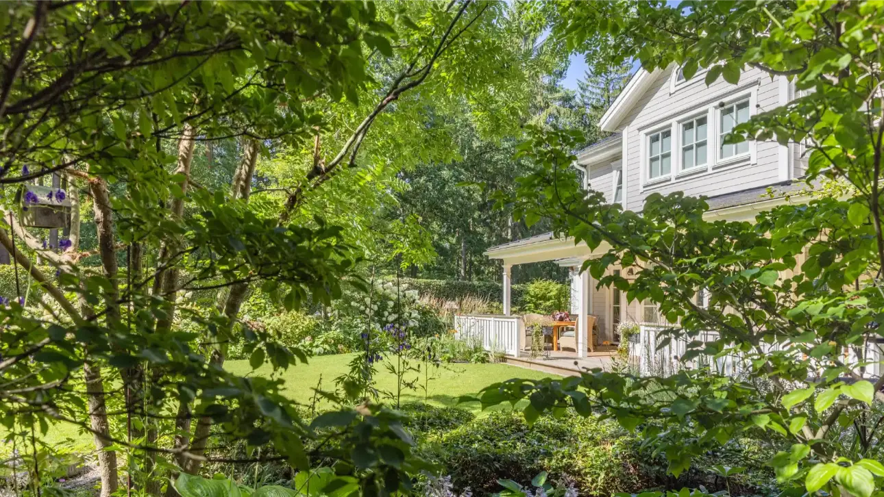 Ein modernes Haus mit einem gepflegten Garten, umgeben von Bäumen und Pflanzen.