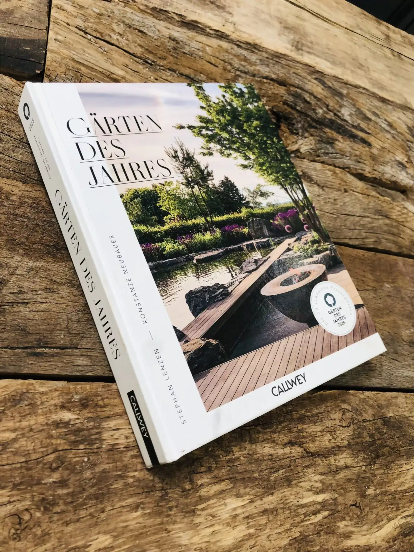 Gärten des Jahres von Callwey auf rustikalem Holztisch Auf dem Holztisch liegt schräg das Buch „Gärten des Jahres“ von Callwey mit Gartenfoto auf dem Cover und der 2025-Auszeichnung.
